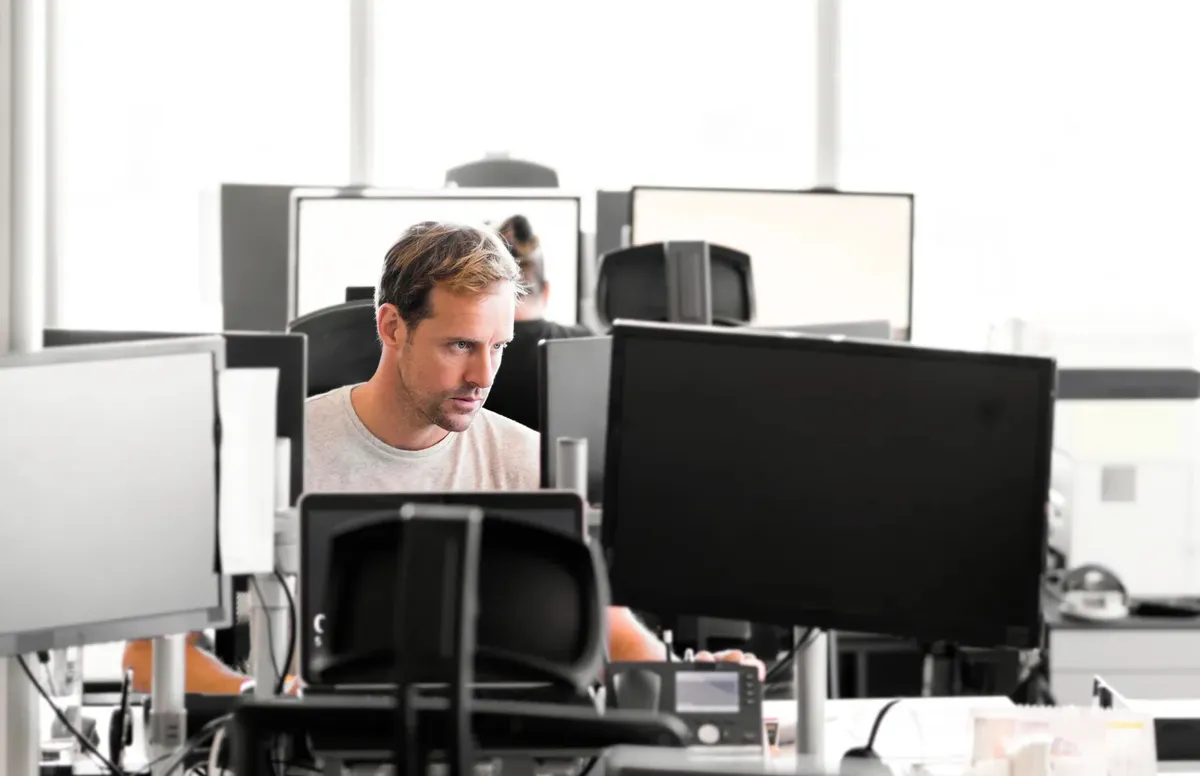Professional werkt geconcentreerd achter meerdere monitoren
