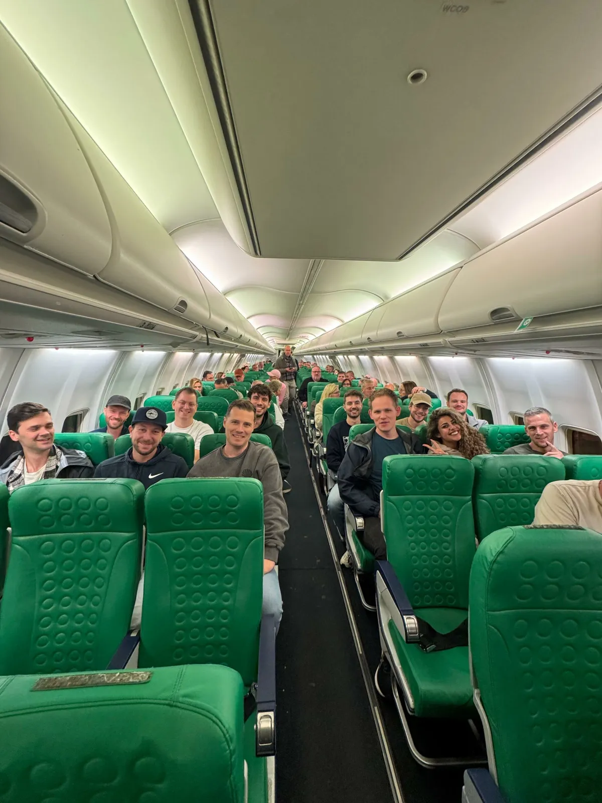 Groepsfoto van het team in het vliegtuig