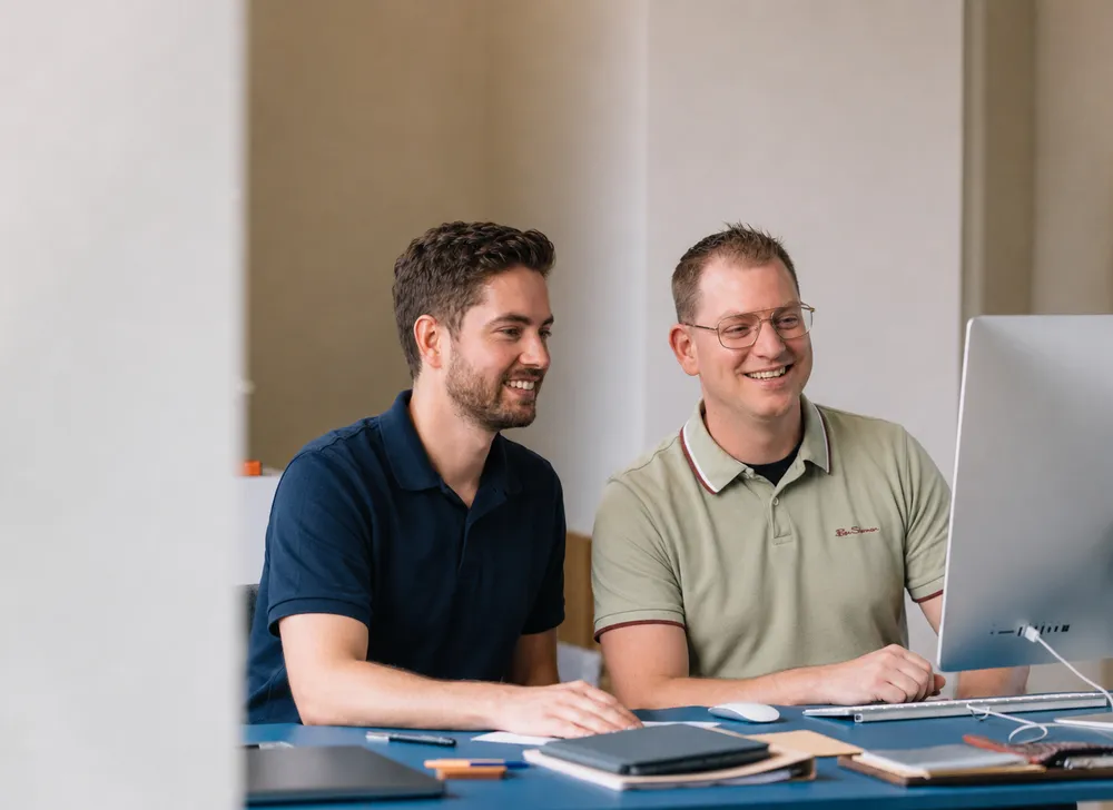 Twee consultants werken samen Twee consultants werken samen achter een iMac op kantoor