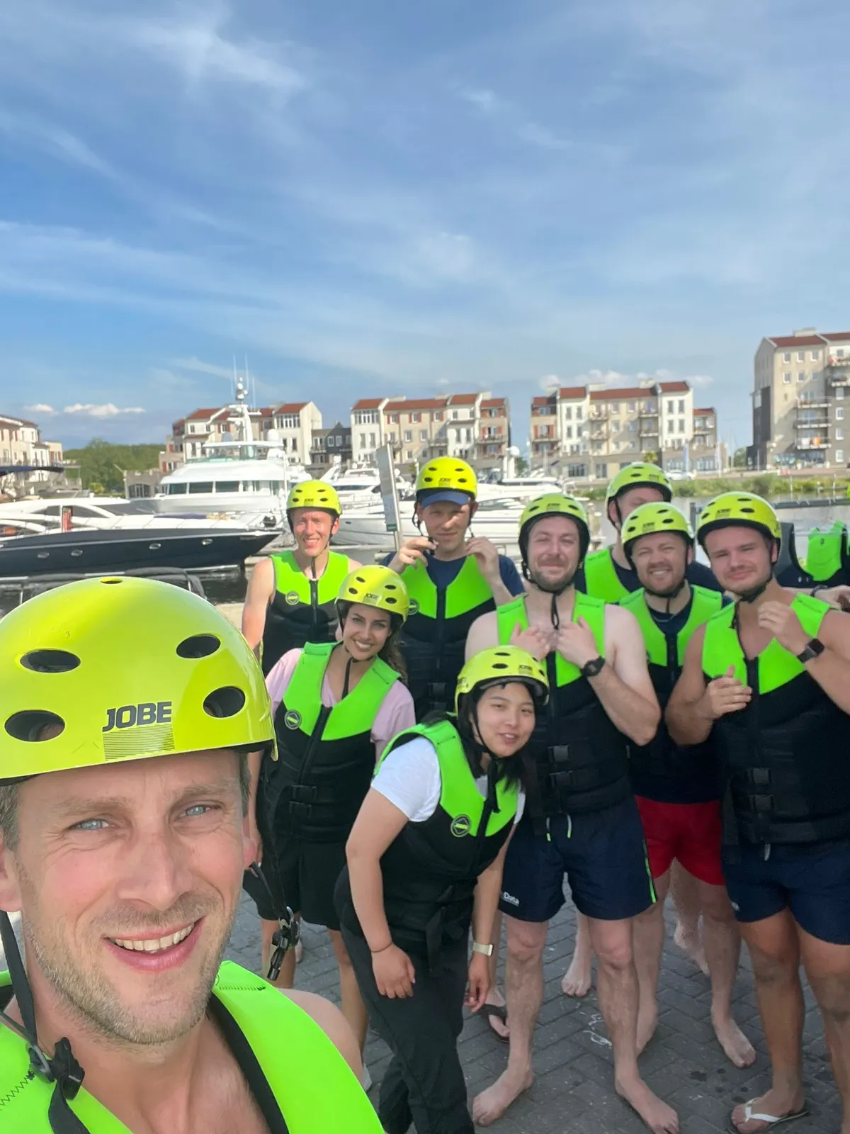 Teamfoto in de haven met veiligheidshelmen en zwemvesten